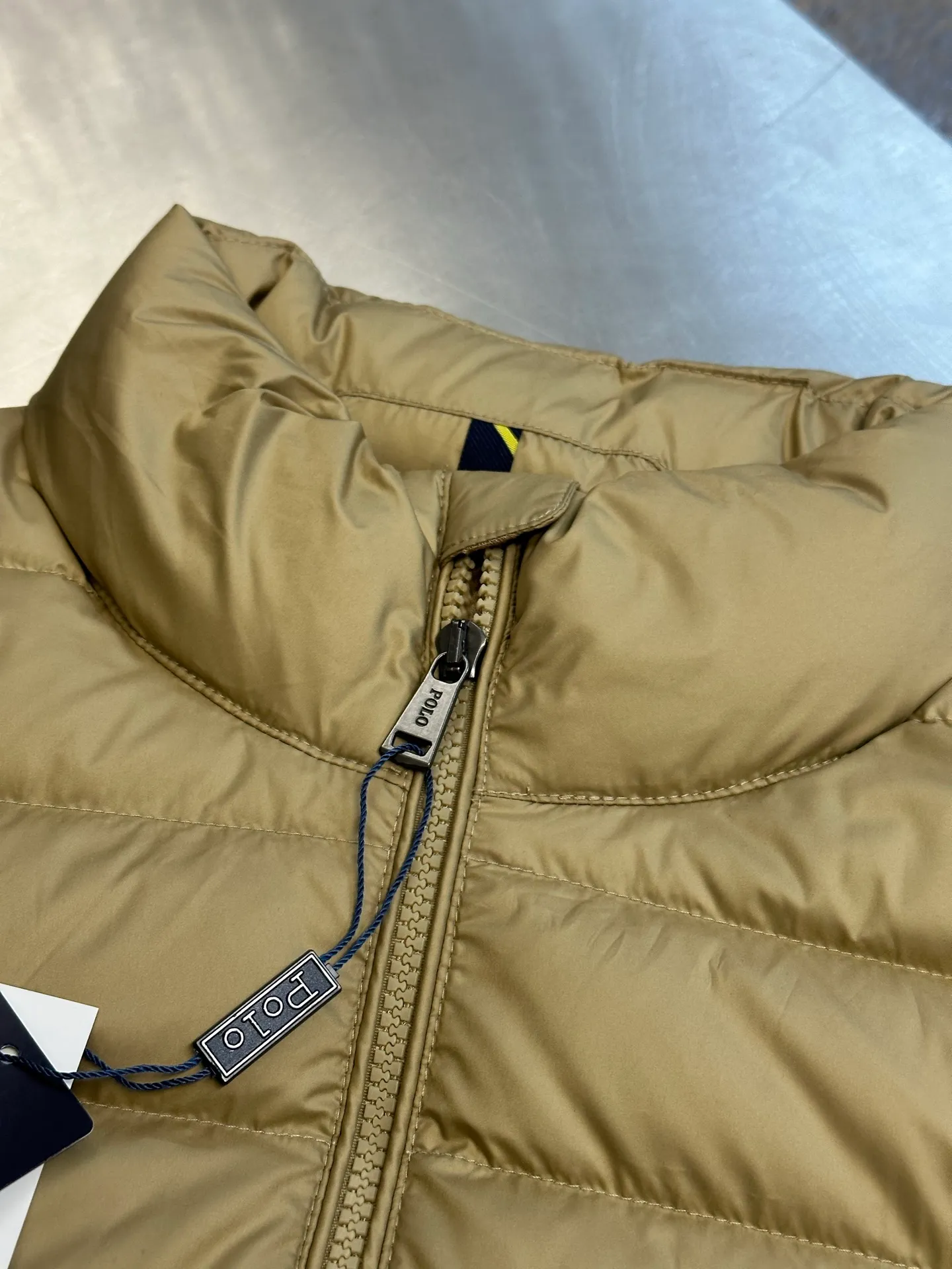 P890 Ralph Lauren lightweight down jacket. The nylon fabric has good windproof and waterproof properties, which can effectively block the intrusion of wind and rain from the outside and keep the inside dry. It is suitable for wearing in humid or rainy environments. The red label on the chest is made with an imported MECLO embroidery machine. The original pattern is scanned first, and then high-quality silk thread is used to make a pattern. The density effect is adjusted by continuous pattern making.  The zipper design is simple and elegant, easy to operate, and the closing design of the cuffs and hem effectively prevents cold wind from invading, improving the warmth and comfort of wearing. It uses 90 white duck down with a weight of 260g to ensure excellent thermal insulation performance. After strict screening and processing, the velvet is not easy to drill, ensuring durability. size: s m l xl